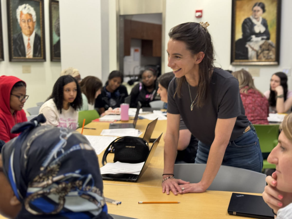 Stephanie working with a room of students at a long classroom table