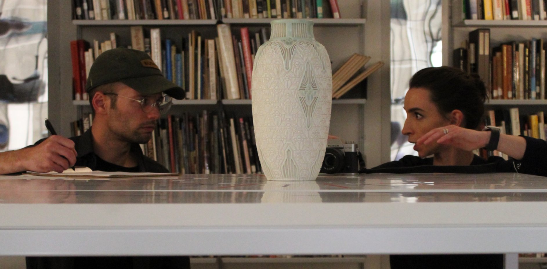 Stephanie and Isaac sitting across a table from each other evaluating a 3D-printed Scarab Vase replica