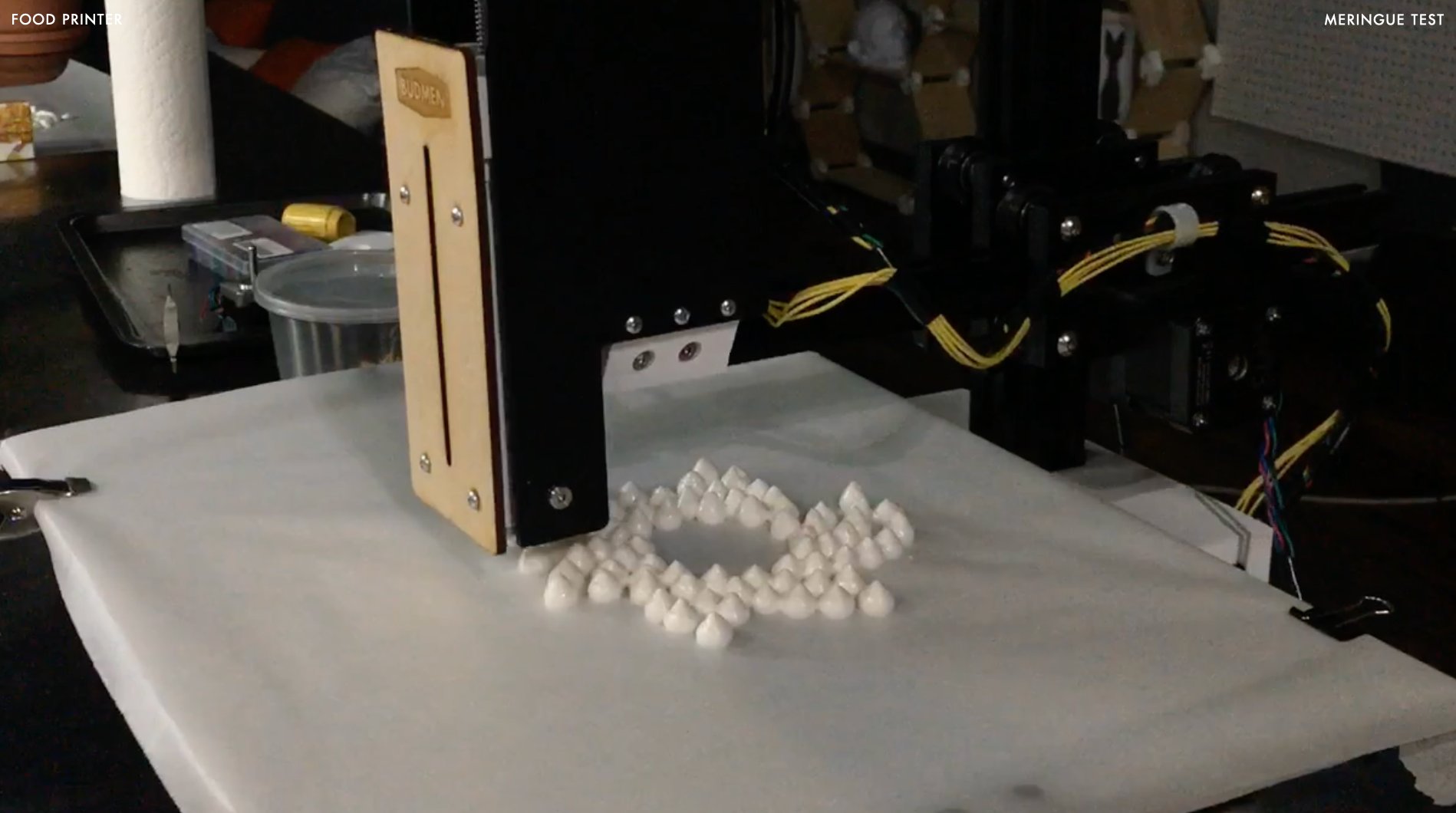 The food printer mid-print, depositing meringue dollops