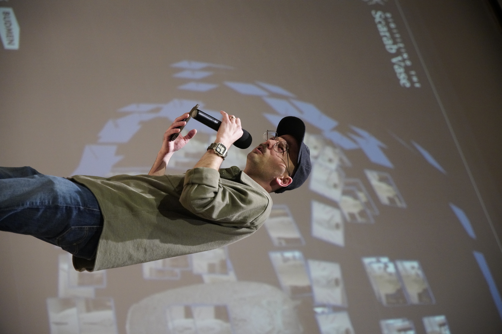 Isaac on stage with photogrammetry slides projected behind him